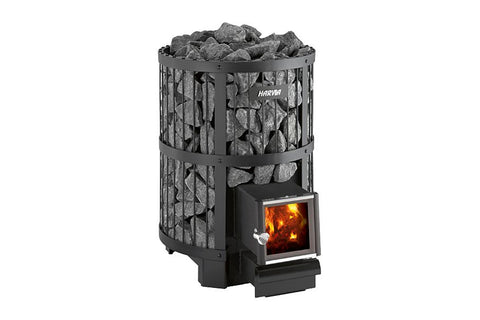 Black cylindrical wood-burning sauna stove with gray rocks on top, viewing window showing flames, and Harvia branding on whit