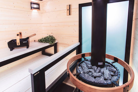 Curved black sauna light with clear frosted lens and natural wood trim, shown with product packaging on white background