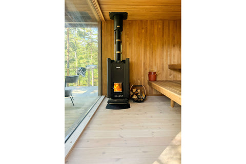 Harvia Linear 28 black wood-burning sauna stove with visible flames in front window and gray stones in top chamber