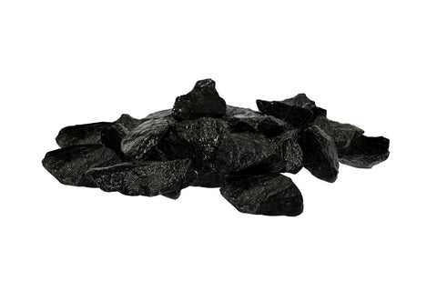Pile of black vulcanite sauna heater stones with irregular angular shapes on white background