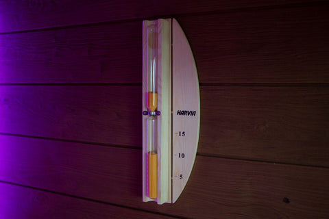 Harvia Sandglass Lux sauna timer with wooden frame, metal band, and red sand in glass tube on white background