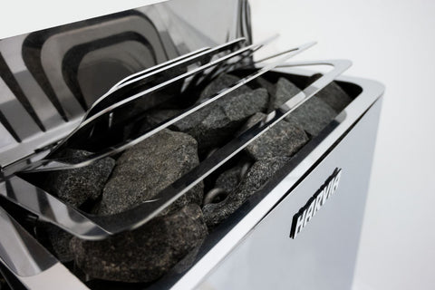 Harvia The Wall electric sauna heater in stainless steel with open top showing black stones inside, on white background