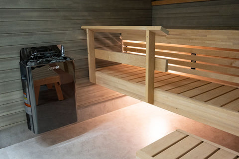 Harvia The Wall black steel electric sauna heater with open lid showing heated rocks inside, on white background