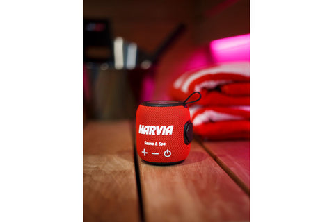 Red fabric Harvia sauna speaker with black accents, metallic top, control buttons, and carrying loop on white background