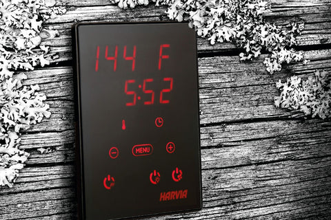 Harvia Xenio black digital sauna control unit with red LED display showing 144°F and 5:52, multiple control buttons on weathe