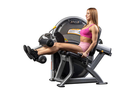 Hoist Club Line Leg Curl machine with gray metal frame, black padded seat, and leg extension attachments on white background