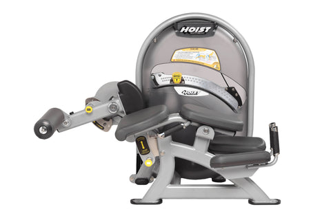 Hoist Standing Prone Leg Curl machine with gray frame, black padded seat and leg curl attachment, yellow safety labels, on wh