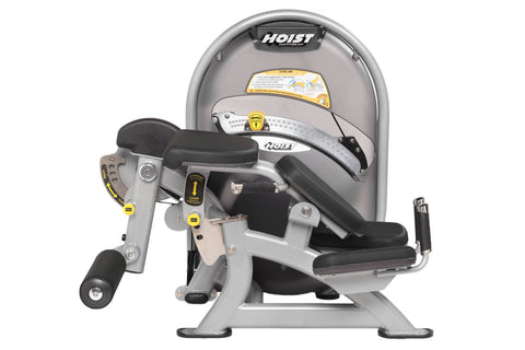 Hoist Standing Prone Leg Curl machine with gray frame, black padded seat and leg curl attachment, yellow safety labels, on wh