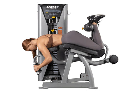 Hoist ROC-IT Prone Leg Curl Machine with silver frame, black padded seat and leg extension arm with weight stack on white bac