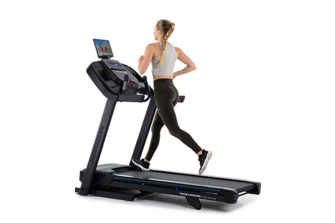 Black motorized treadmill with digital display console, handrails, and cushioned running belt on white background