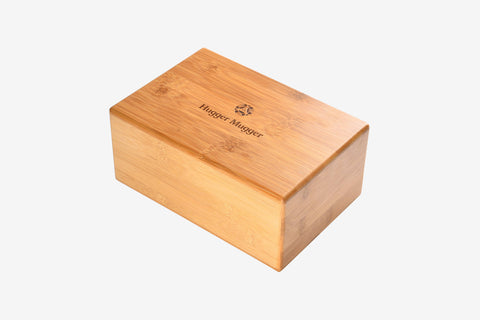 Natural bamboo yoga block with Hugger Mugger logo engraved on front, displayed on white background