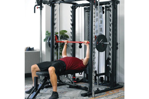 Black and silver multi-functional Smith cage system with red pull-up bar, dual cable stations, and weight stack on white back