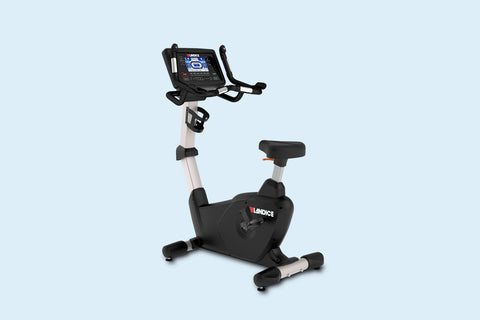 Landice U7 upright exercise bike with black frame, beige center post, digital console display, and foot pedals on light blue 
