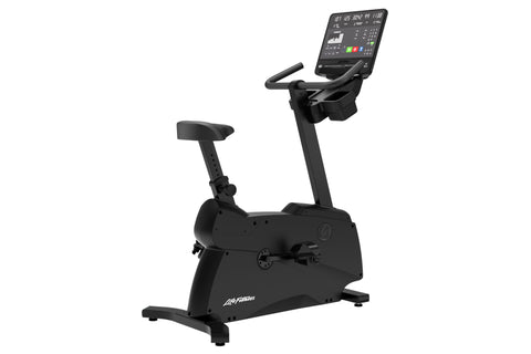 Black upright stationary exercise bike with digital console display, padded seat, handlebars, and stabilizing base on white b