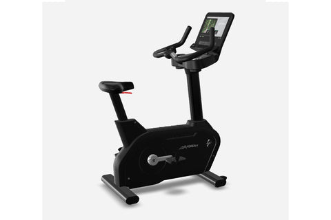 Black upright exercise bike with digital touchscreen display showing workout metrics, padded seat, handlebars, and foot pedal