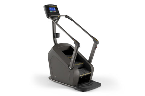 Black Matrix stair climber machine with digital display console, dual handrails with gold accents, and stepped platform on wh