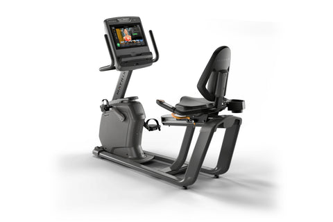 Black and gray Matrix recumbent exercise bike with digital display screen and padded seat, shown on white background
