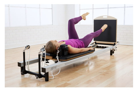 Merrithew SPX Home Pilates Reformer with black platform, wooden footbar, dual black domes, white frame, and included accessor
