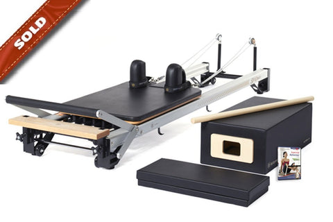 Black and cream Merrithew SPX home pilates reformer with carriage, footbar, and accessories on white background, marked sold