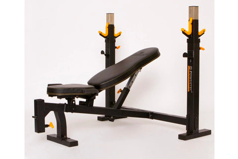 Black and yellow Olympic weight bench with dual squat racks and adjustable leg extension, on white background