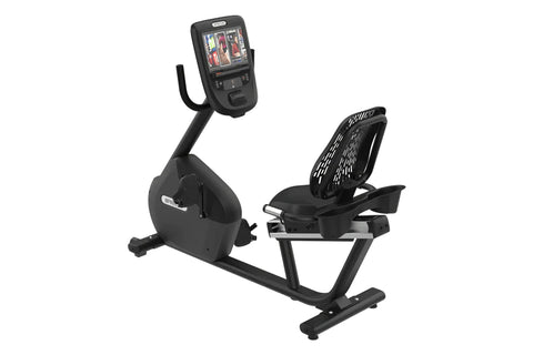 Black recumbent exercise bike with digital display console showing workout metrics, perforated backrest, and footrest on whit