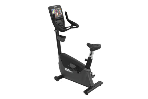 Black upright stationary exercise bike with digital touchscreen console, handlebar grips, and adjustable seat on white backgr