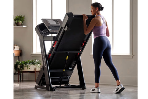 Woman running on black ProForm Plus Trainer 1000 treadmill with digital display in modern home gym setting
