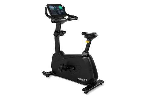 Spirit CU1000ENT black upright stationary exercise bike with digital display console and yellow handlebar accents, on white b