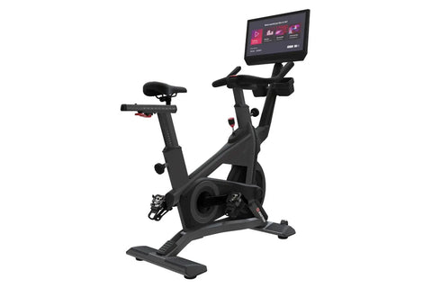 Black stationary exercise bike with digital touchscreen display mounted on upper frame, padded seat, handlebars, and foot ped