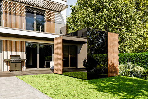 Modern wooden outdoor sauna with vertical slat design positioned on lawn beside contemporary architecture and green hedge wal