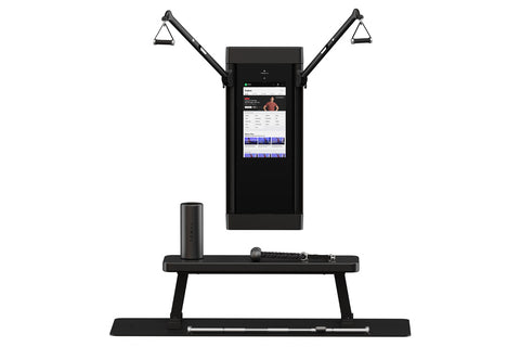 Black Tonal 2 smart home gym with dual articulating arms and grip handles, touchscreen display showing fitness app interface,