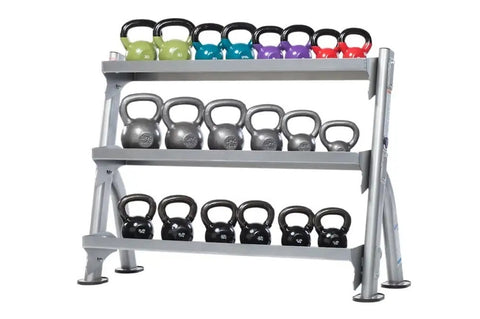 Three-tier gray steel kettlebell storage rack with black handles, holding colorful kettlebells in green, teal, purple, and re
