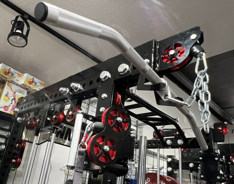 Black metal cable machine with white and gray handles, red pulleys, and silver chain attachment