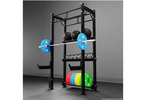 Black modular power rack with pull-up bar, blue barbell with weights loaded, storage shelves holding dumbbells and colored we