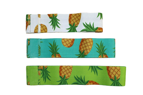Three pineapple-print fabric stretch bands in white, turquoise, and lime green with golden pineapples and green leaves