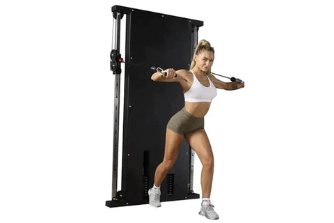 Woman using black wall-mounted cable pulley gym system with dual stacks, performing chest fly exercise with resistance cables