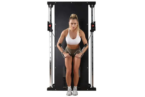 Woman using black wall-mounted cable pulley gym system with dual stacks, performing chest fly exercise with resistance cables