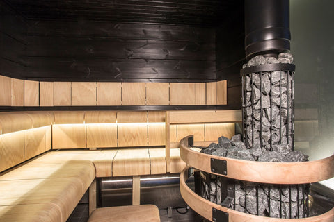 Harvia Legend 150 black cylindrical wood-burning sauna stove with gray rocks on top and glowing fire visible through front do