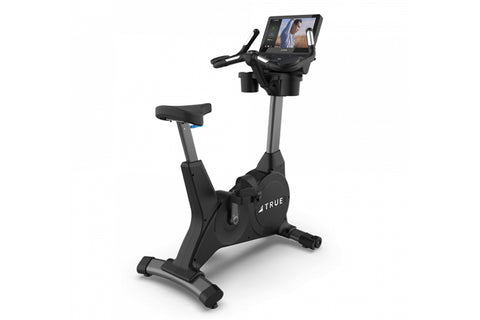 TRUE 900 upright exercise bike with black frame, gray column, padded seat, and digital display console on white background