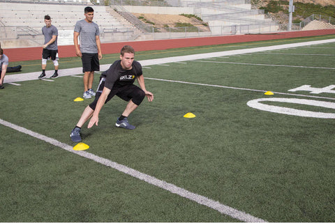 Stack of agility training cones in yellow, red, white, and black with black carrying handle on white background