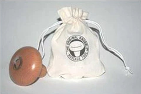 Cream drawstring pouch with circular logo badge next to brown wooden massage ball, on gray background