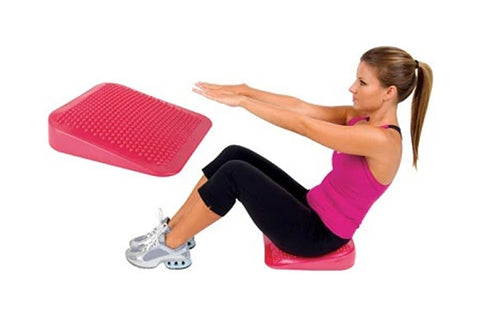 Pink textured balance wedge with model demonstrating use during abdominal exercise on white background