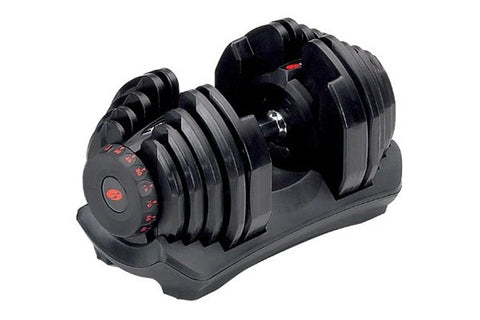 Bowflex SelectTech adjustable dumbbell with black weight plates and red numbered dial, resting on gray base, front view