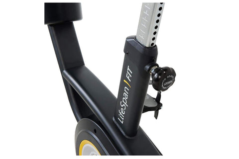 Black upright exercise bike with yellow and gray resistance wheel, black padded seat and handlebars, displayed on white backg