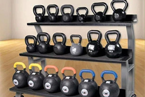 Three-tier metal kettlebell rack holding black kettlebells in various sizes with yellow, red, and blue handles displayed on w
