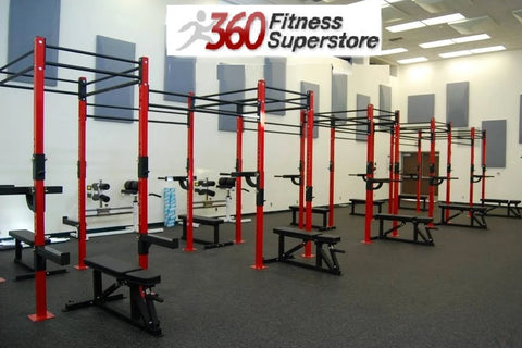 Red and black commercial pull-up bar rig with multiple stations and black benches in fitness facility