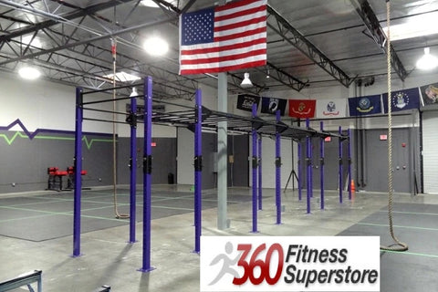 Purple and black pull-up rig with multiple bars in industrial fitness facility, American flag overhead