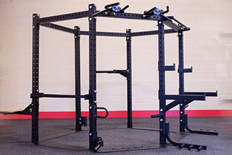 Black steel hexagonal squat rack with blue attachment brackets and pull-up bars, on gym flooring