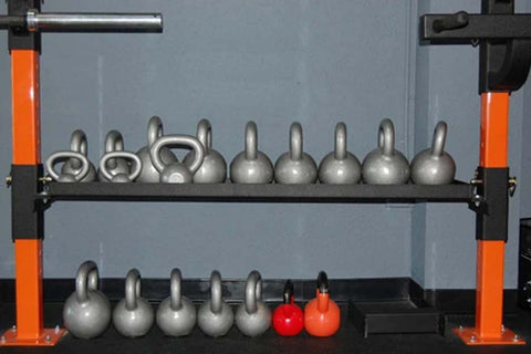 Orange and black kettlebell rack with metal frame holding silver and red kettlebells on two tiers, flat lay view