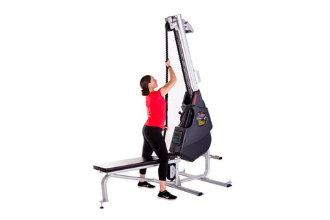 Woman in red shirt using black and silver rope trainer machine with digital display on white background